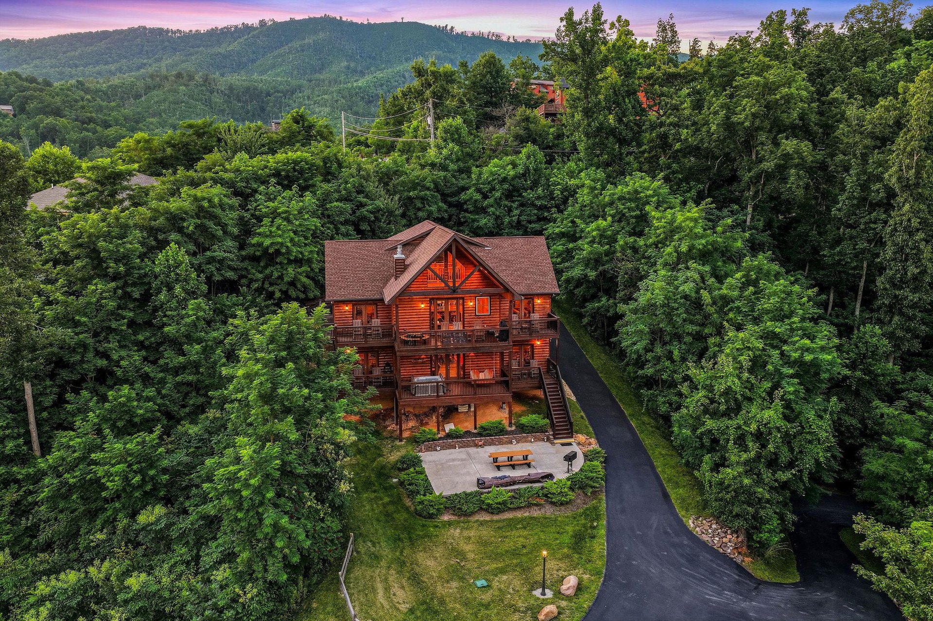 Nestled among rolling forested hills, this stunning mountain lodge offers peaceful privacy with spacious outdoor areas, paved parking, and captivating sunset views over the surrounding landscape.