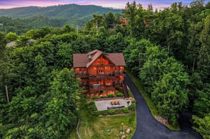 Nestled among rolling forested hills, this stunning mountain lodge offers peaceful privacy with spacious outdoor areas, paved parking, and captivating sunset views over the surrounding landscape.