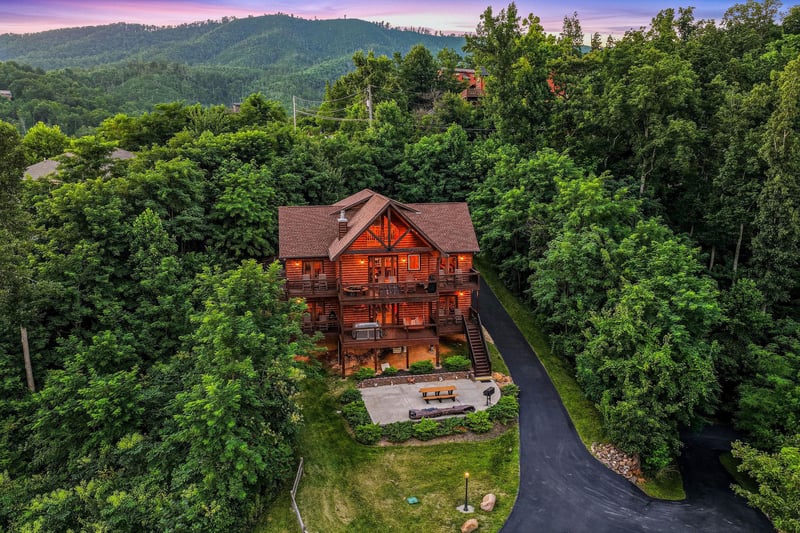 Nestled among rolling forested hills, this stunning mountain lodge offers peaceful privacy with spacious outdoor areas, paved parking, and captivating sunset views over the surrounding landscape.
