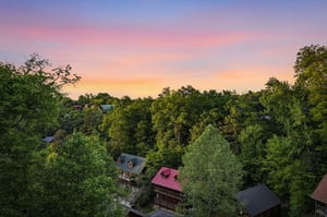 Stunning sunset paints the sky in vibrant hues above this peaceful forested neighborhood, creating a picturesque backdrop for your mountain retreat.