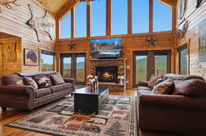 Sink into plush leather sofas by the stone fireplace, gazing through soaring windows at mountain peaks rolling into the distance—your perfect retreat awaits.
