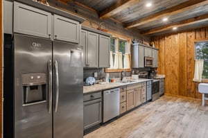 Your fully equipped kitchen features modern appliances, ample counter space, and rustic wood finishes—perfect for preparing meals while enjoying charming natural light through the windows.