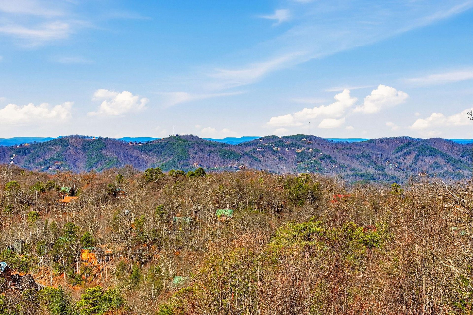 Rolling mountains create a stunning backdrop across forested hills and scattered homes in this peaceful rural setting.