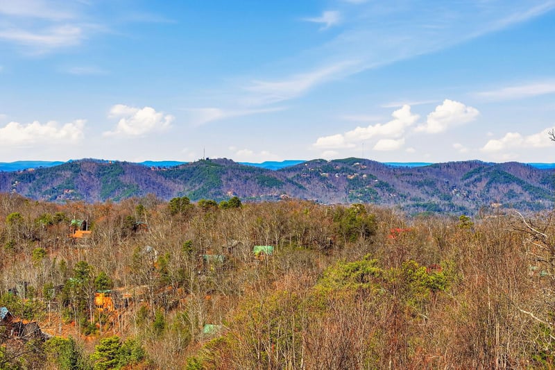 Rolling mountains create a stunning backdrop across forested hills and scattered homes in this peaceful rural setting.