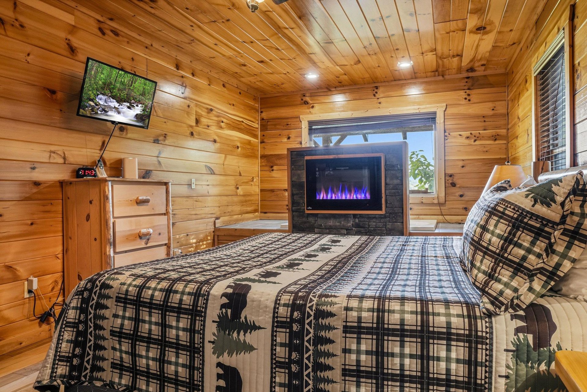 Warm wood walls surround your cozy retreat, where you can unwind in bed with the soothing glow of a modern fireplace and watch your favorite shows on the wallmounted TV.