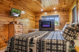 Warm wood walls surround your cozy retreat, where you can unwind in bed with the soothing glow of a modern fireplace and watch your favorite shows on the wallmounted TV.