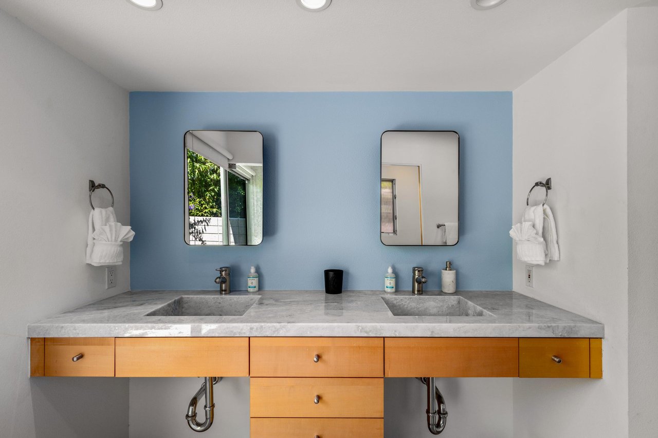 Stunning primary bathroom with dual vanity sink, large sliding doors with natural lighting, and standalone shower with its own sliding door to turn it into an indooroutdoor shower.
