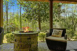 Unwind on your private covered patio with cozy seating around a crackling fire pit, surrounded by lush forest views.