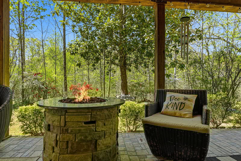 Unwind on your private covered patio with cozy seating around a crackling fire pit, surrounded by lush forest views.