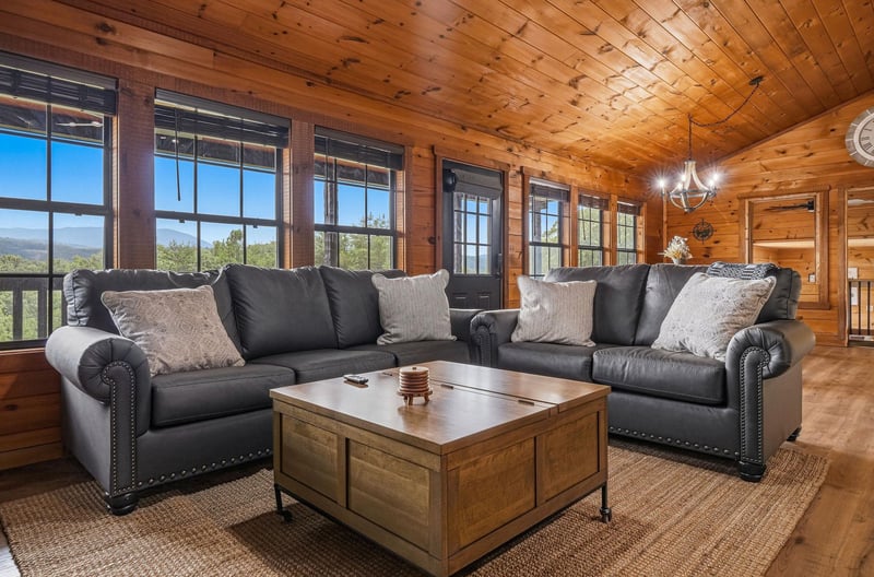 Sink into comfortable leather seating in your warm, woodpaneled living room. Large windows frame natural views, creating a peaceful retreat for relaxing with loved ones.