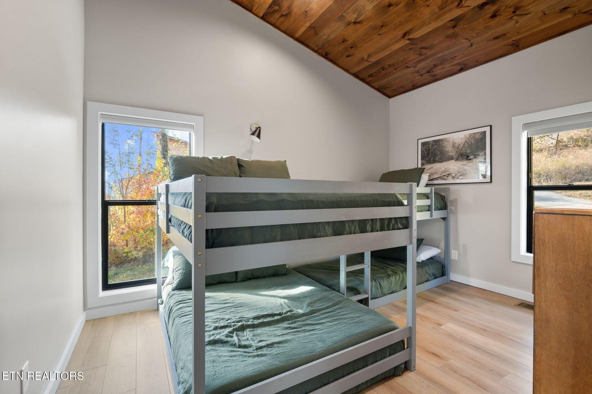 A cozy bedroom where rustic wood ceilings meet modern comfort. Your crew will love the bunk beds while you enjoy peaceful views of autumn foliage through the generous windows.