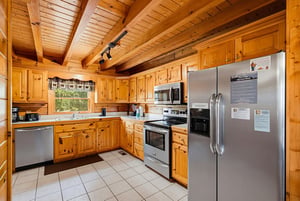 Your fullyequipped kitchen features warm pine cabinetry, stainless steel appliances, and vaulted beamed ceilings that create a cozy mountain retreat atmosphere perfect for preparing meals.