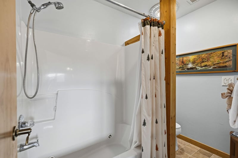 Fresh, clean bathroom with charming pine tree curtains and rustic wood touches for your mountain retreat comfort.