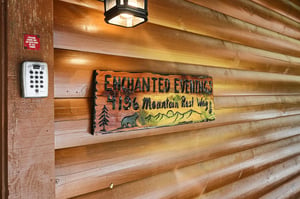 Entrance to Enchanted Evenings cabin, located at 4196 Mountain Rest Way. This rustic wooden sign marks the front entrance of the property, complete with keyless entry and exterior lighting.