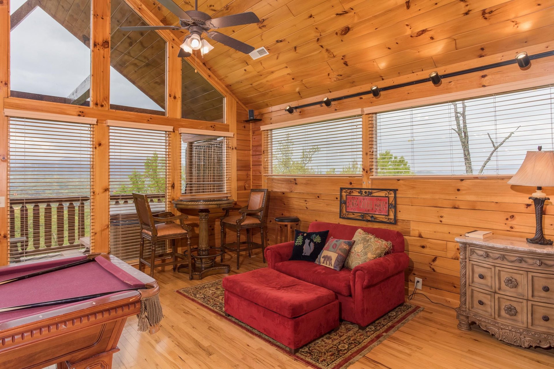 Table and two chairs, oversized chair with ottoman, and pool table in the loft space at Howlin in the Smokies, a 2 bedroom cabin rental located in Pigeon Forge
