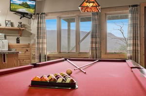 Challenge friends to pool while soaking in breathtaking mountain views through expansive windows in your cozy game room retreat.