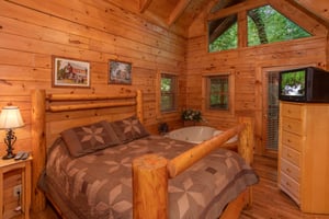 Bedroom with queensized log bed and a heartshaped jacuzzi at Dreams Do Come True, a 1bedroom cabin rental located in Pigeon Forge