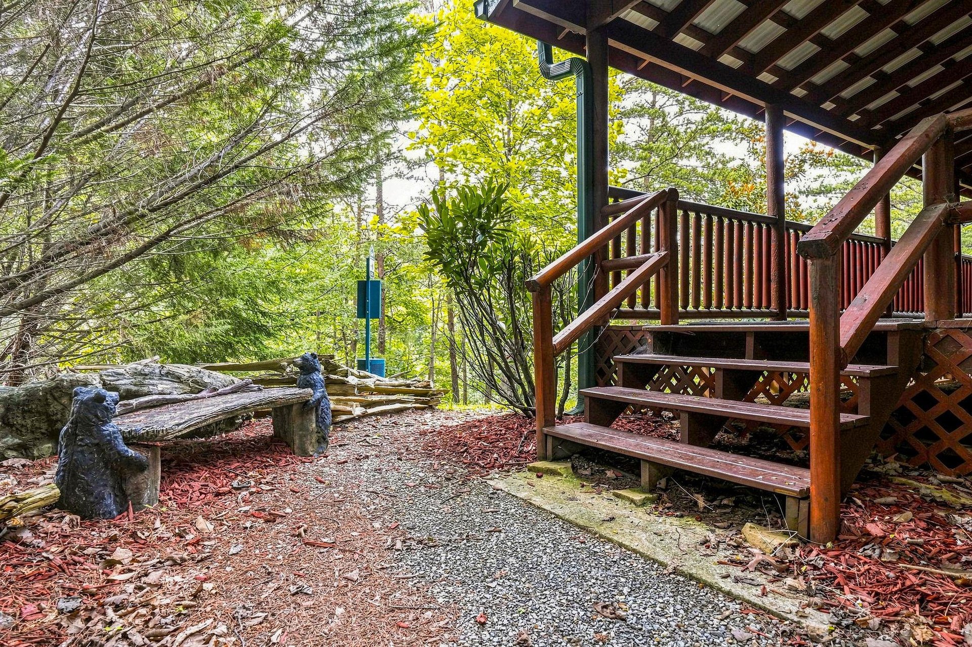 A rustic wooden deck extends into a tranquil forest setting, where carved bear sculptures and mosscovered logs blend with the surrounding trees—a peaceful place to step outside and feel truly immerse