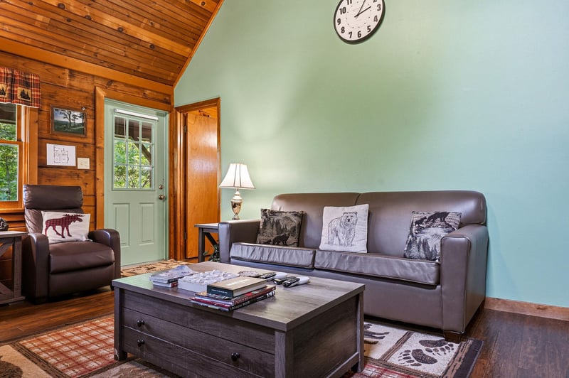Relax in your cozy living room with leather seating, rustic wood beams, and warm cabin charm for perfect mountain getaway moments.