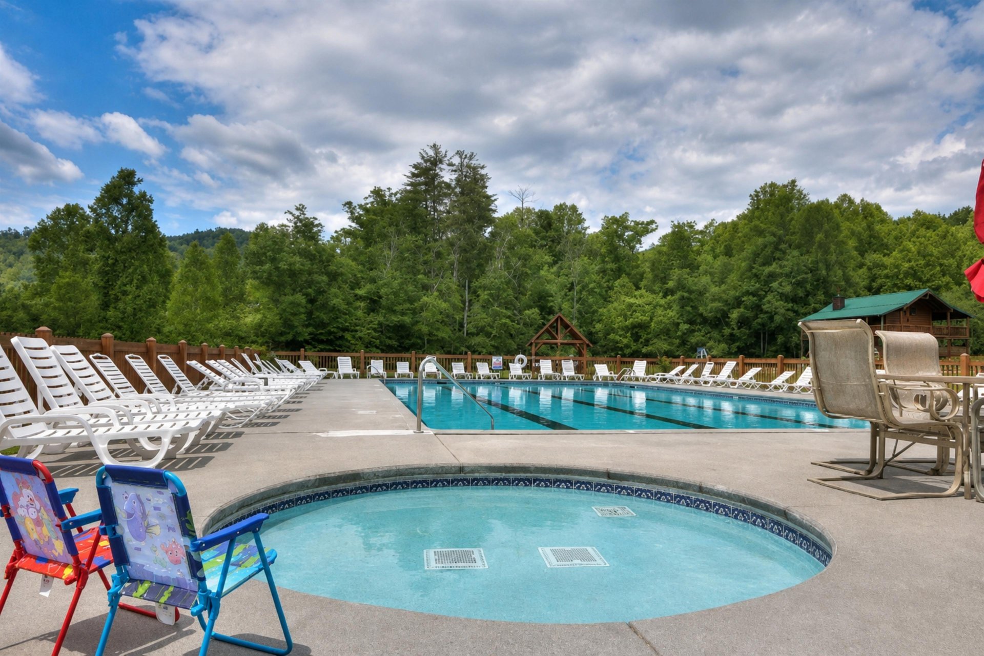 A serene mountain pool retreat surrounded by lush forests, with a spacious main pool and a relaxing hot tub.