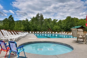 A serene mountain pool retreat surrounded by lush forests, with a spacious main pool and a relaxing hot tub.