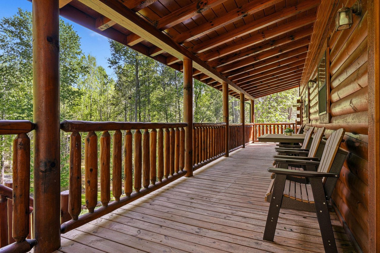 Relax on your private covered deck with rustic wooden chairs overlooking peaceful forest views.