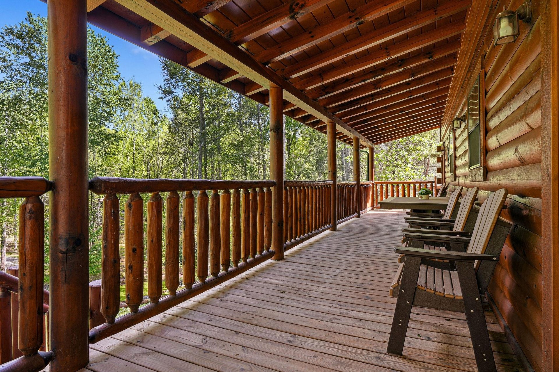 Relax on your private covered deck with rustic wooden chairs overlooking peaceful forest views.