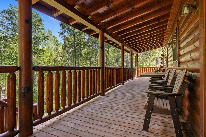 Relax on your private covered deck with rustic wooden chairs overlooking peaceful forest views.