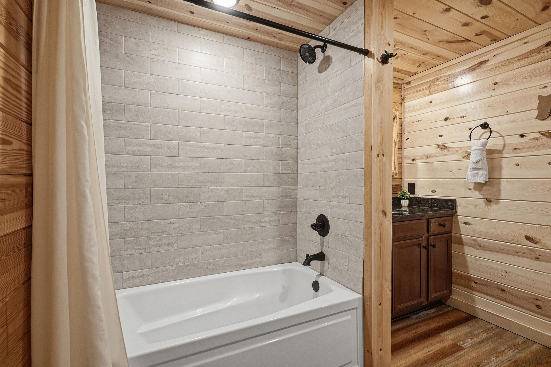 Your private bathroom awaits with a sleek tubshower combo, spalike tile, rustic wood accents, and fresh towels ready for your arrival.