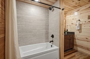 Your private bathroom awaits with a sleek tubshower combo, spalike tile, rustic wood accents, and fresh towels ready for your arrival.