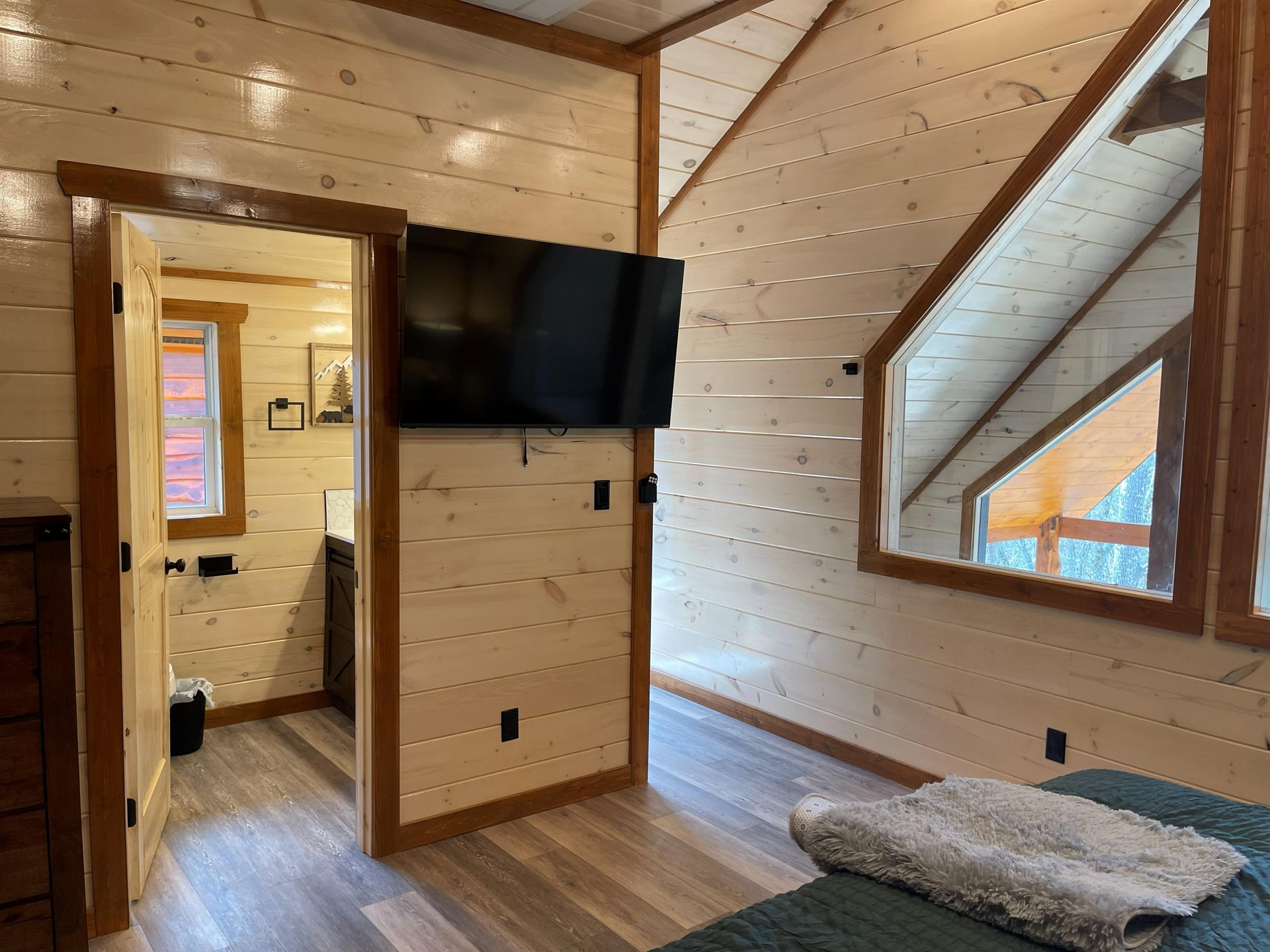 Cozy up in your rustic loft bedroom with warm wood walls and your own wallmounted TV for peaceful evening relaxation.