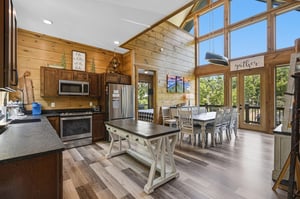 Gather around this stunning open kitchen with soaring windows that flood your space with natural light and forest views.