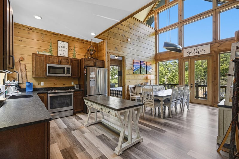 Gather around this stunning open kitchen with soaring windows that flood your space with natural light and forest views.