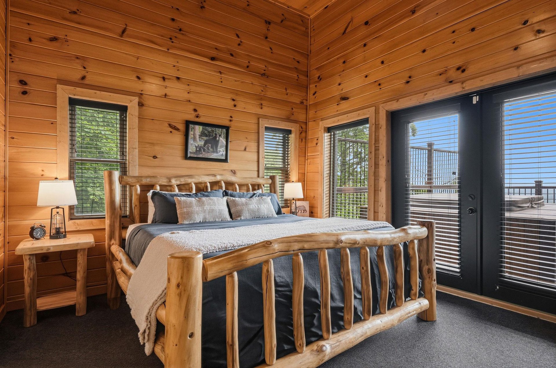 Unwind in your private bedroom retreat featuring a handcrafted log bed, warm pine walls, and doors opening to your own balcony with sweeping mountain vistas.