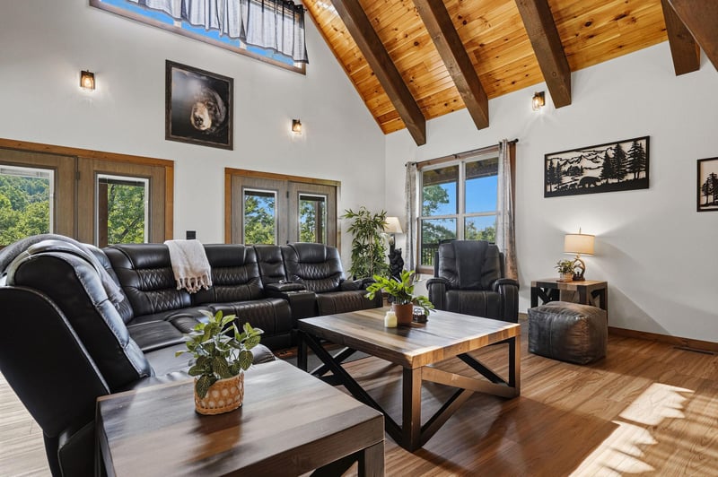 Sink into the leather sofa and soak in the soaring vaulted ceilings and bright natural light pouring through the windows, framing a peaceful wooded view.