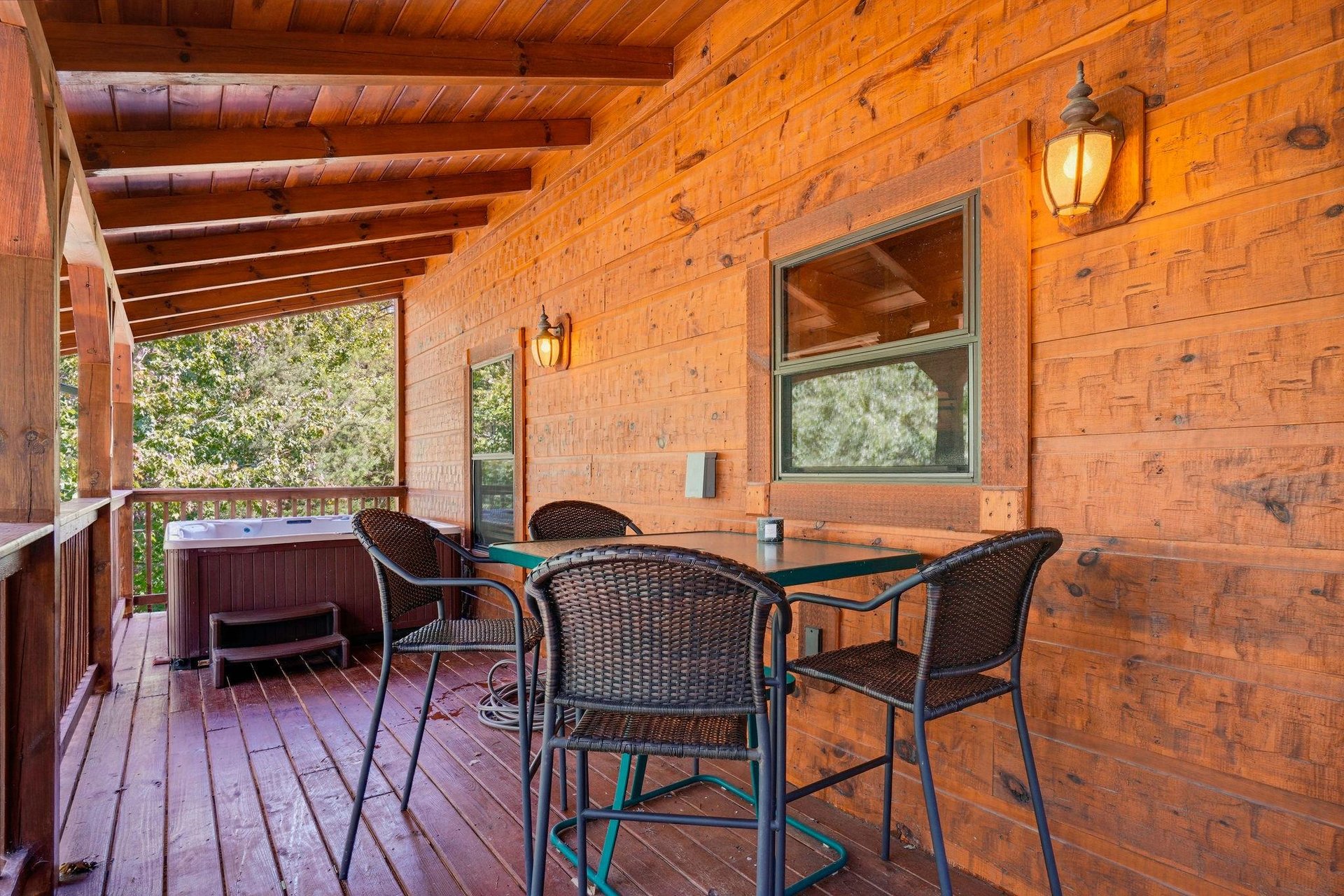 Unwind on your private covered deck, complete with a dining table and hot tub, surrounded by rustic wood and forest views.