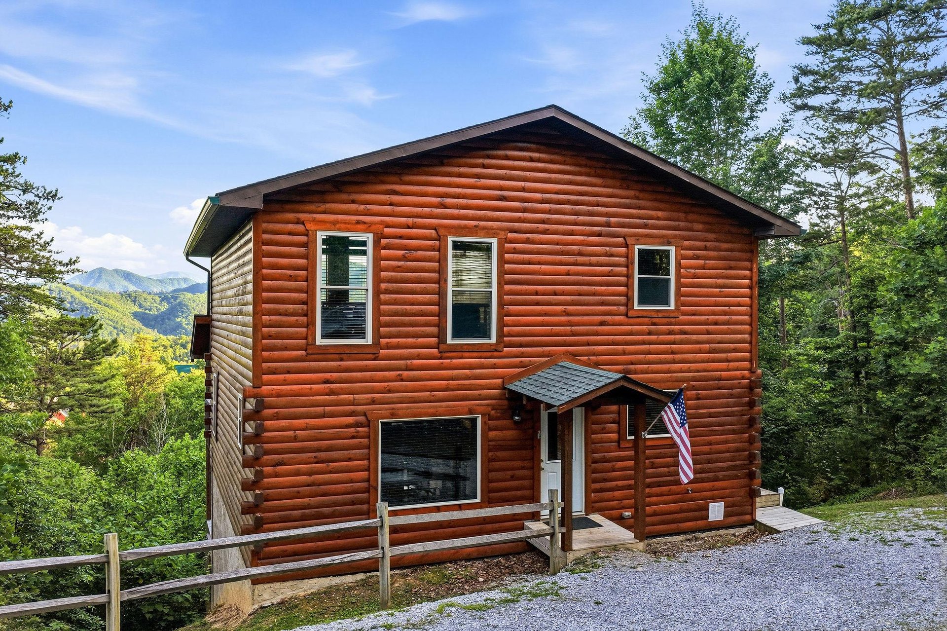 Twostory log cabin nestled among trees with mountain views, offering a peaceful retreat surrounded by lush greenery and scenic landscapes.