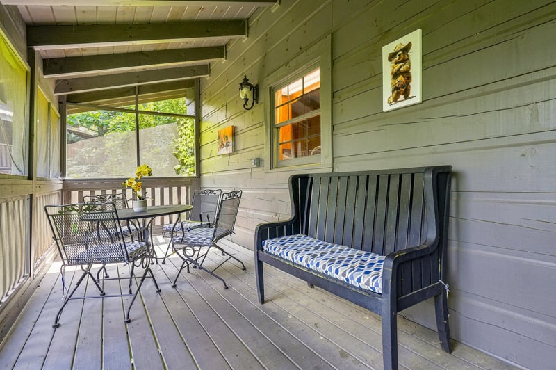 Your private porch invites you to savor morning coffee at the bistro table or unwind on the cushioned bench, surrounded by peaceful tree views and charming rustic details.