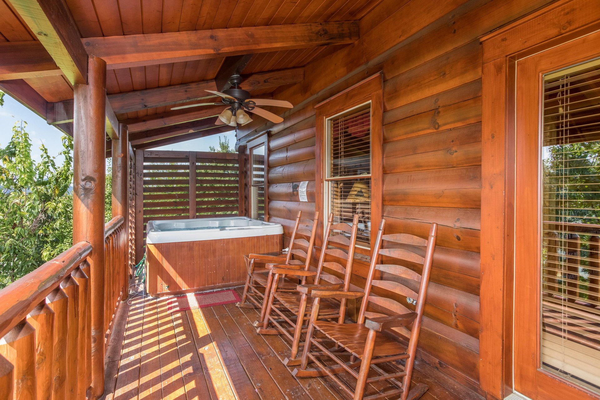 Deck with a hot tub and rocking chairs at Graceland, a 4bedroom cabin rental located in Pigeon Forge