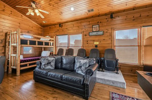 Relax in your cozy cabin den with theater seating, a leather sofa, and a rustic bunk bed—perfect for movie nights or settling in after adventure.