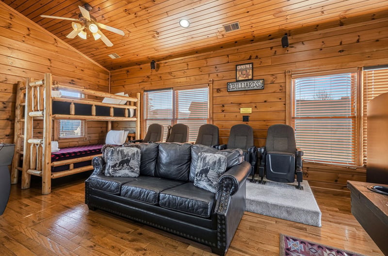 Relax in your cozy cabin den with theater seating, a leather sofa, and a rustic bunk bed—perfect for movie nights or settling in after adventure.