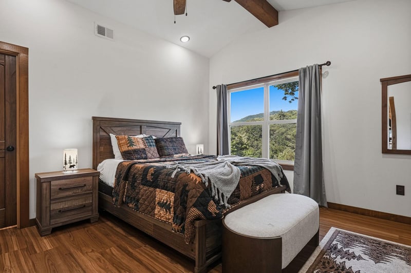 Wake up in this cozy bedroom with warm wood accents and vaulted ceilings. Your mountain view framed by the window invites peaceful mornings and serene evenings.