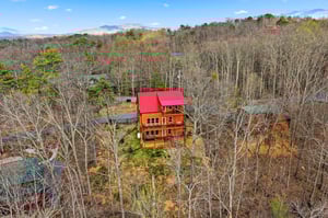 Mountain cabin nestled among autumn trees with distant peaks creating a serene woodland setting.