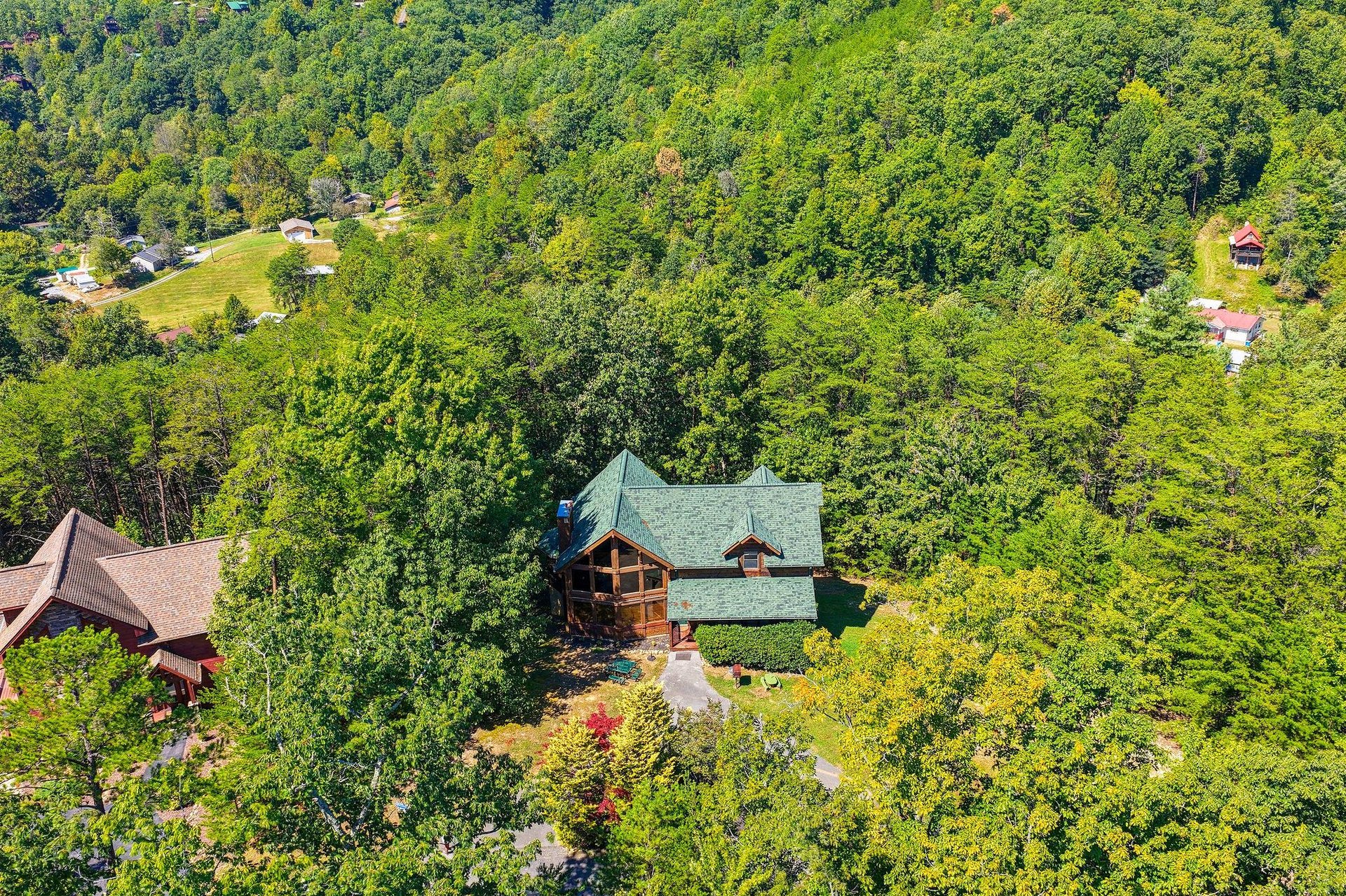 An aerial view captures the property nestled among lush forest, offering a secluded mountain escape with natural beauty all around.