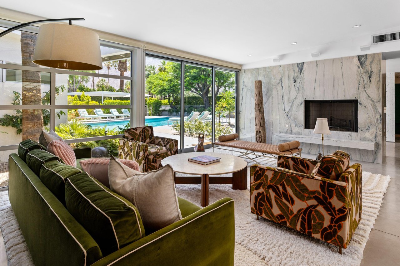 Beautiful living room that looks out to the pool and spa. Featuring a fireplace, sliding doors, and openconcept living.