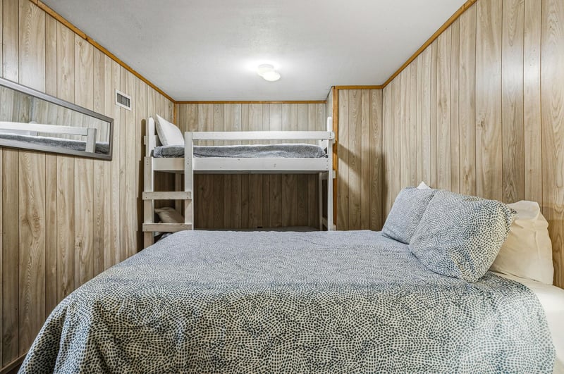 Rest peacefully in your cozy bedroom with warm wood paneling, comfortable bedding, and spacesaving bunk beds for extra guests.