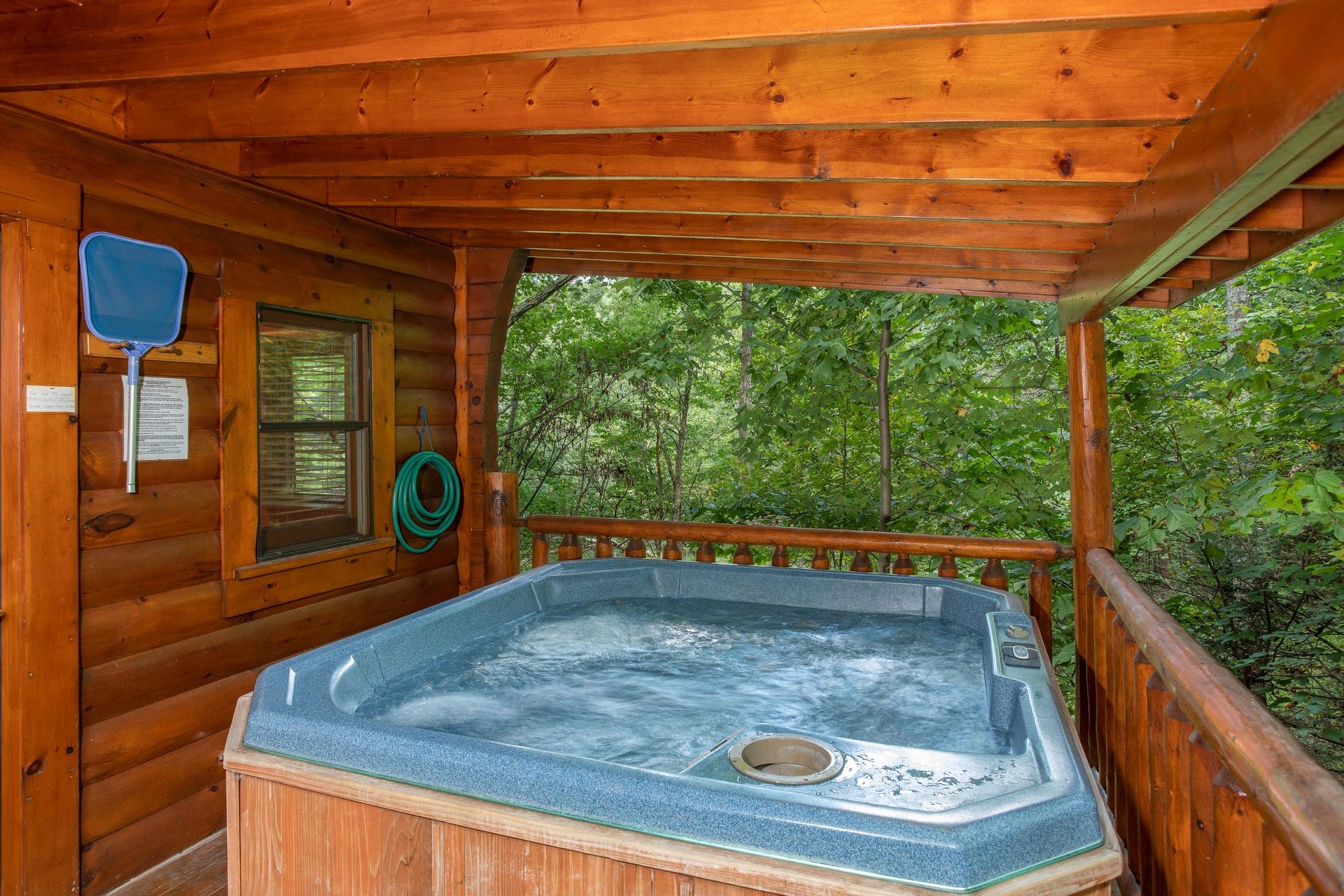Hot tub on a covered deck surrounded by woods at Dreams Do Come True, a 1bedroom cabin rental located in Pigeon Forge