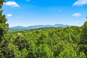 A stunning natural landscape surrounds the property with mountain ridges visible against the skyline and lush forested hillsides spanning the horizon.