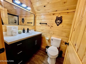 Step into this cozy cabin bathroom featuring rich wood walls, modern fixtures, and playful wolf decor that adds rustic charm to your mountain getaway.