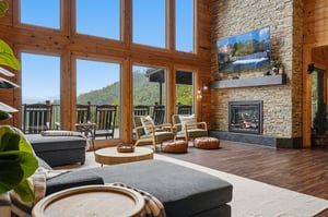 Sink into plush seating beside your stone fireplace and soak in sweeping mountain views through soaring windows—your perfect retreat for peaceful mornings and cozy evenings.